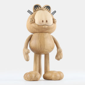 Wooden figurine of an animated cartoon cat character carved from light oak, featuring a rounded head with engraved facial details, stylized ears with black markings, short whisker lines, a rounded sculpted body, simplified limbs, visible natural wood grain, and a matte surface on a plain white background.