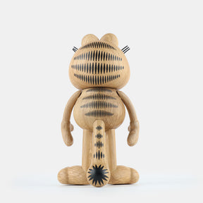Back view of a wooden figurine of an animated cartoon cat character carved from light oak, featuring engraved black stripe patterns across the head, body, and tail, rounded sculpted limbs, visible natural wood grain, and a matte surface on a plain white background.