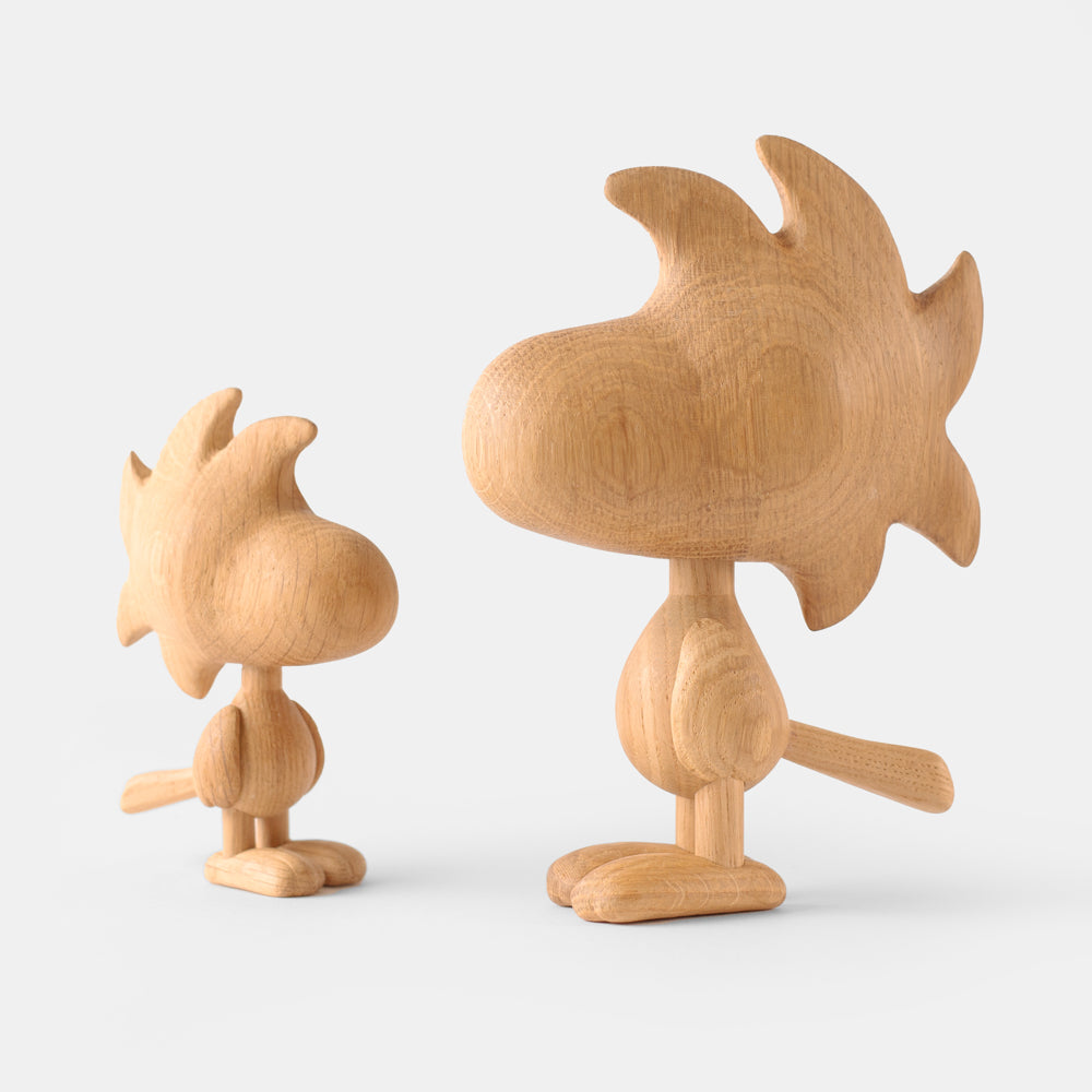 Two wooden figurines of animated cartoon characters carved from light oak, featuring rounded heads, stylized shapes, simplified bodies and tails, visible natural wood grain, and smooth matte surfaces on a plain white background.