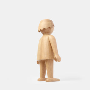 Wooden Playmobil-style human figure crafted from light oak, showing simplified proportions, a rounded head with carved hair detail, smooth sculpted arms and legs, visible natural wood grain, and a matte surface on a plain white background.