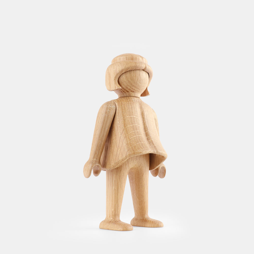 Wooden Playmobil-style girl figure made from light oak, featuring simplified proportions, a rounded head with carved hair detail, smooth sculpted arms and legs, visible natural wood grain, and a matte surface on a plain white background.