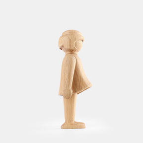 Wooden Playmobil-style girl figure made from light oak, featuring simplified proportions, a rounded head with carved hair detail, smooth sculpted arms and legs, visible natural wood grain, and a matte surface on a plain white background.