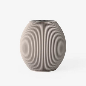 A ribbed ceramic vase in a warm taupe-beige color, featuring vertical fluted ridges and a rounded, bulbous shape, set against a plain white background.