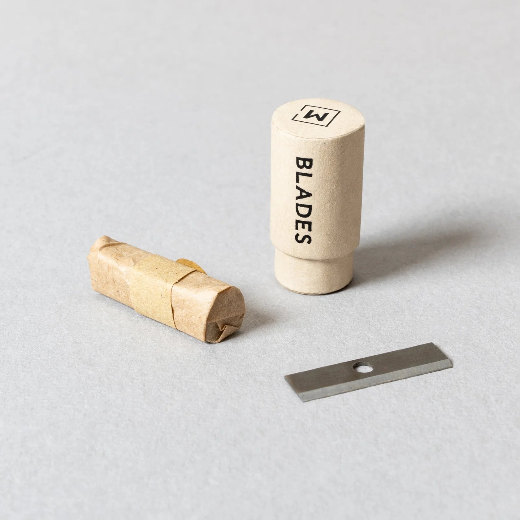 Set of blades with a cylindrical container labeled 'BLADES' on a light gray background