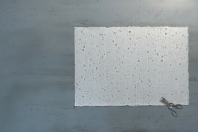 A sheet of washi paper with a textured, dotted pattern laid out flat next to a pair of scissors.