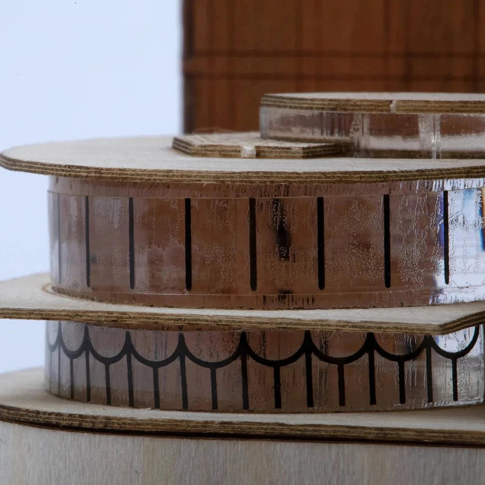 Cardboard model of a building with decorative elements on a plain background