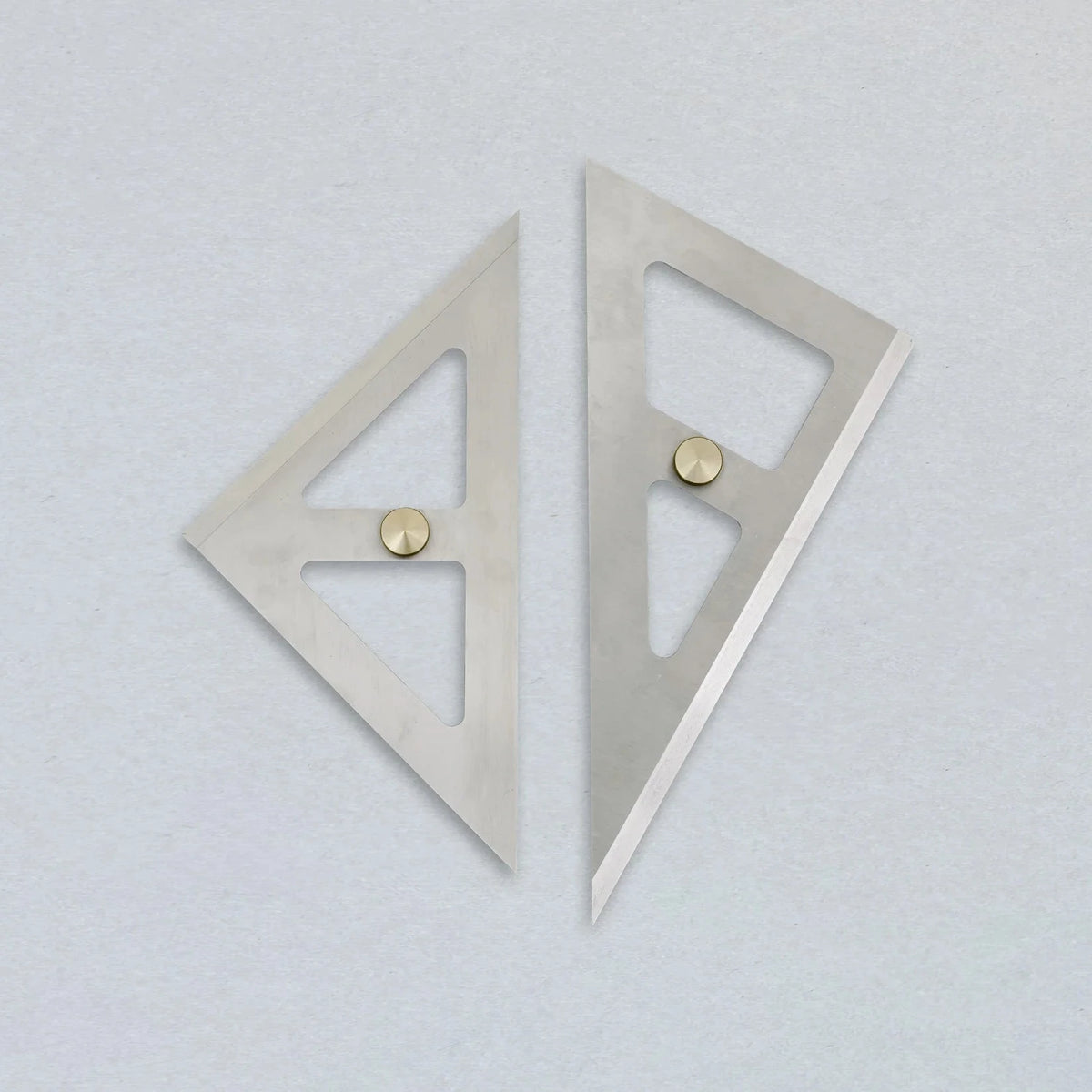 Two metallic square rulers on a light gray background