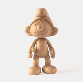 Wooden figurine of a small animated cartoon character, carved from light oak, featuring a rounded hat, smiling facial details, simplified body proportions, visible natural wood grain, and a smooth matte surface on a plain white background.