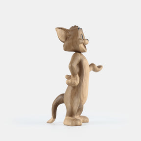 Wooden figurine of an animated cartoon mouse character, carved from light-toned wood, featuring expressive facial details, rounded ears, a standing pose with one hand raised, visible wood grain, and a smooth matte surface on a plain white background.