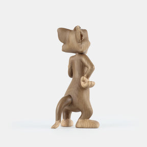 Wooden figurine of an animated cartoon mouse character, carved from light-toned wood, featuring expressive facial details, rounded ears, a standing pose with one hand raised, visible wood grain, and a smooth matte surface on a plain white background.
