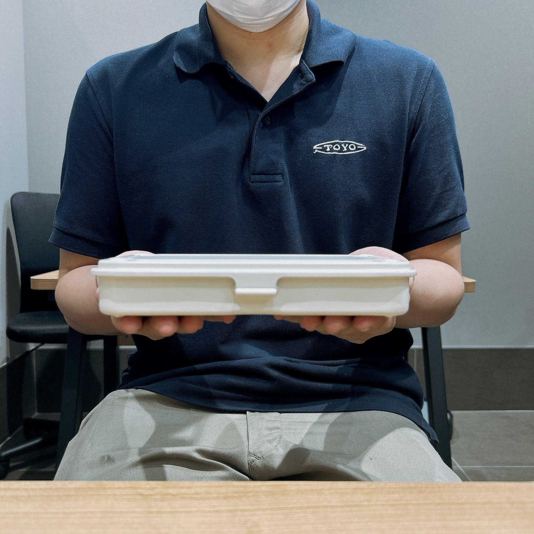 White rectangular storage box with lid held by a person wearing a Toyo logo shirt, showing scale.