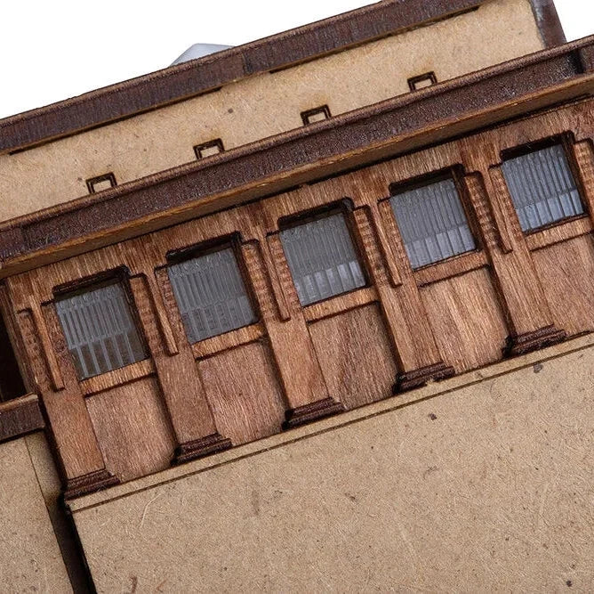 Close-up of a model building with wooden exterior and windows.