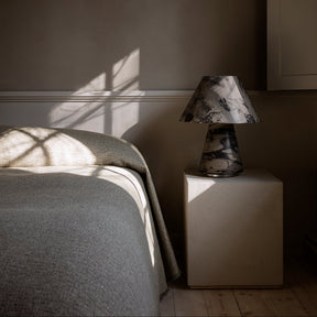 Bedroom with a bed and a lamp on a nightstand against a dark wall.
