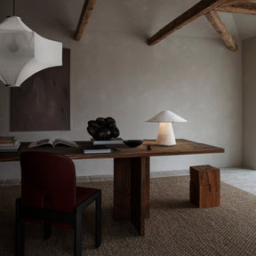 Modern interior with wooden desk, chair, and lamp in a room with exposed beams.