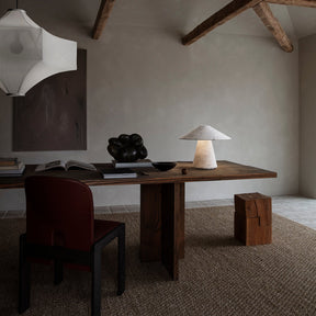 Modern interior with wooden desk, chair, and lamp in a room with exposed beams.
