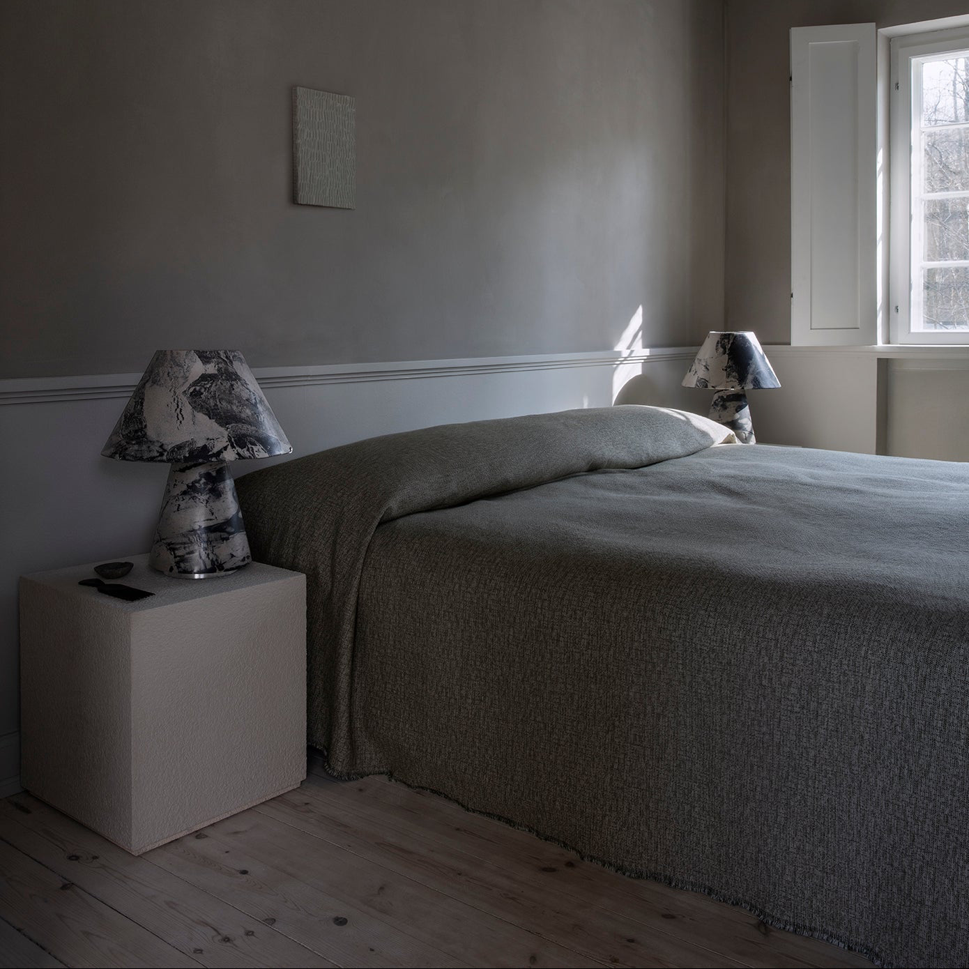 Minimalist bedroom with gray bedding and neutral decor.
