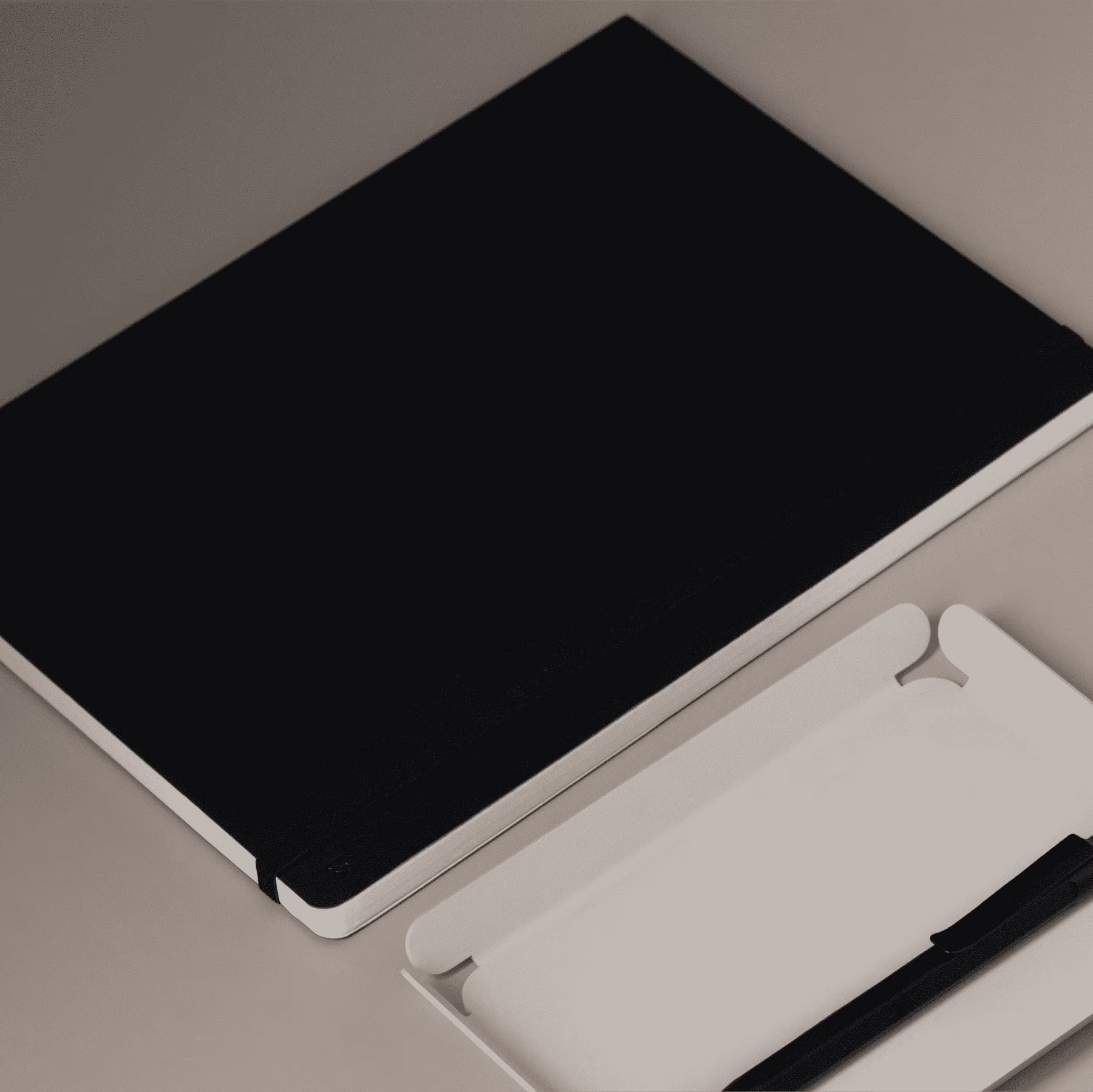 Black tablet with a white stand and pen on a gray surface