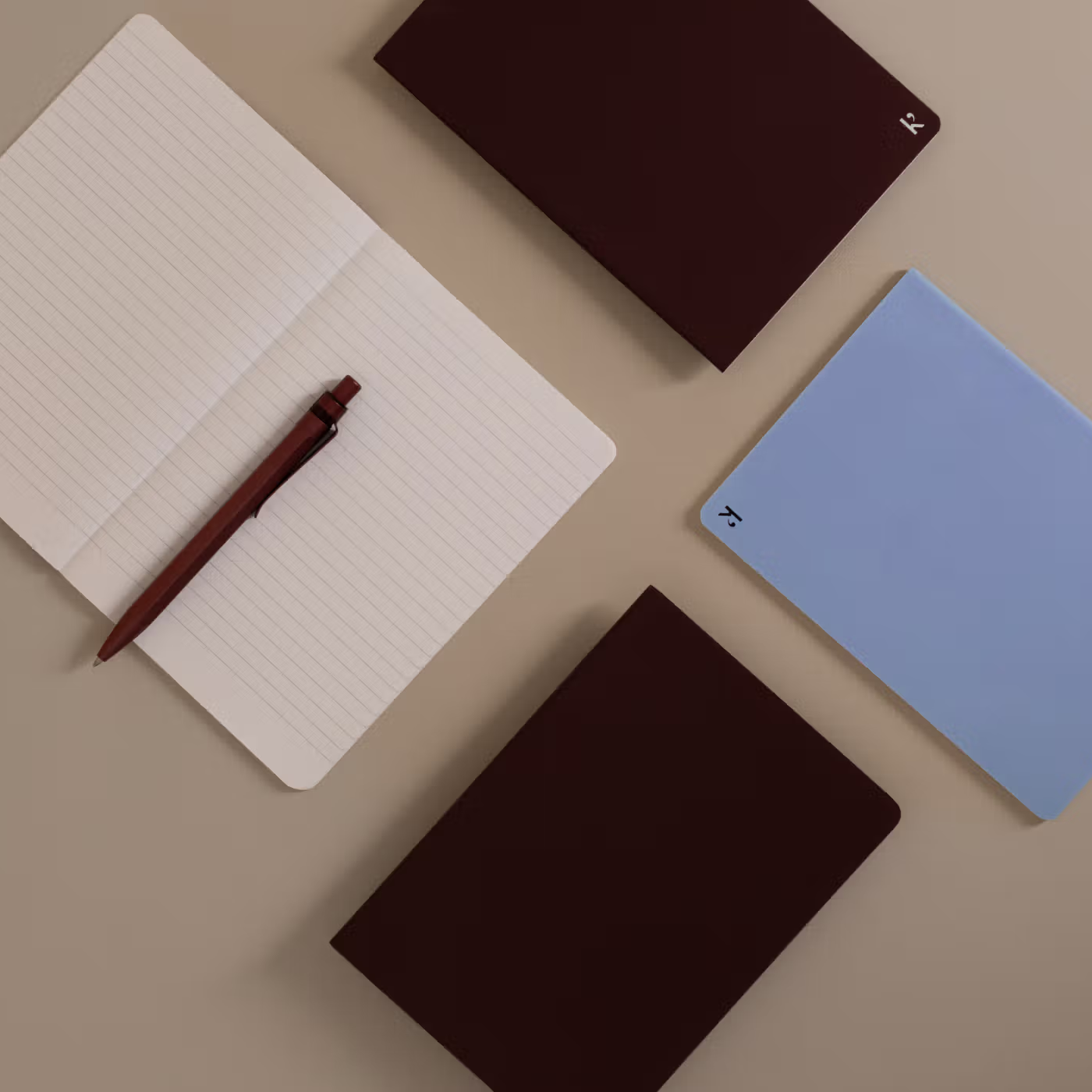 Notebooks and a pen on a beige surface