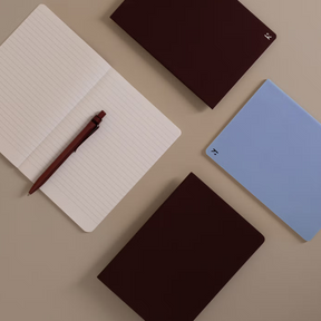Notebooks and a pen on a beige surface