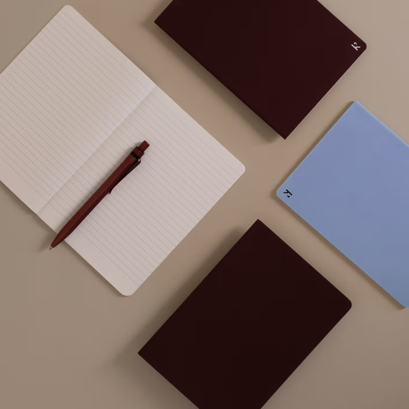 Notebooks and a pen on a beige surface