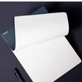 White notebook with a pen on a dark surface