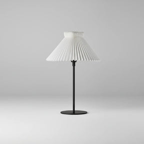 Table lamp with pleated white shade on a gray background