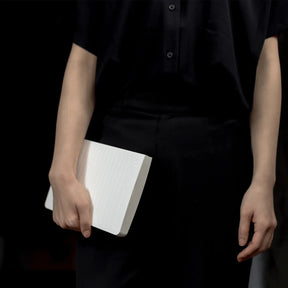Person holding a white book against a dark background