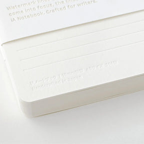 White notebook with embossed text on a light gray background