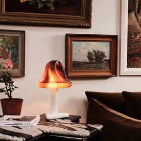 Decorative lamp on a table with framed paintings on the wall