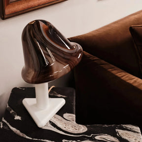 Wooden sculpture on a pedestal in a room with a couch and framed pictures.
