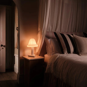 Bedroom with canopy bed and lamp on nightstand, warm lighting
