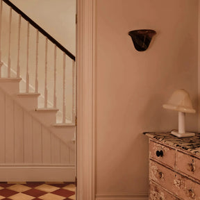 Staircase with a checkered floor and a dresser with a lamp in a room.