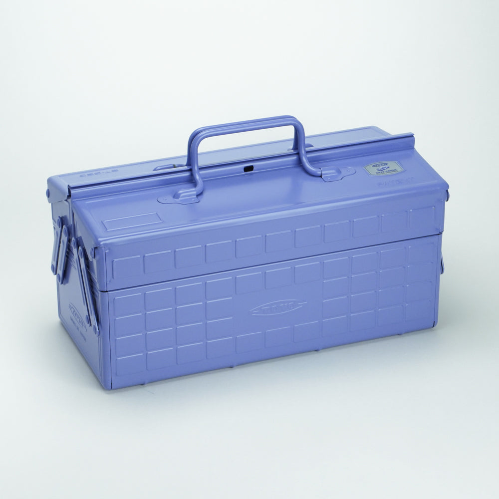 Lilac Toyo steel cantilever toolbox, closed, shown at a three-quarter angle with embossed grid side panels, folded side arms, and a fixed top handle against a white background.