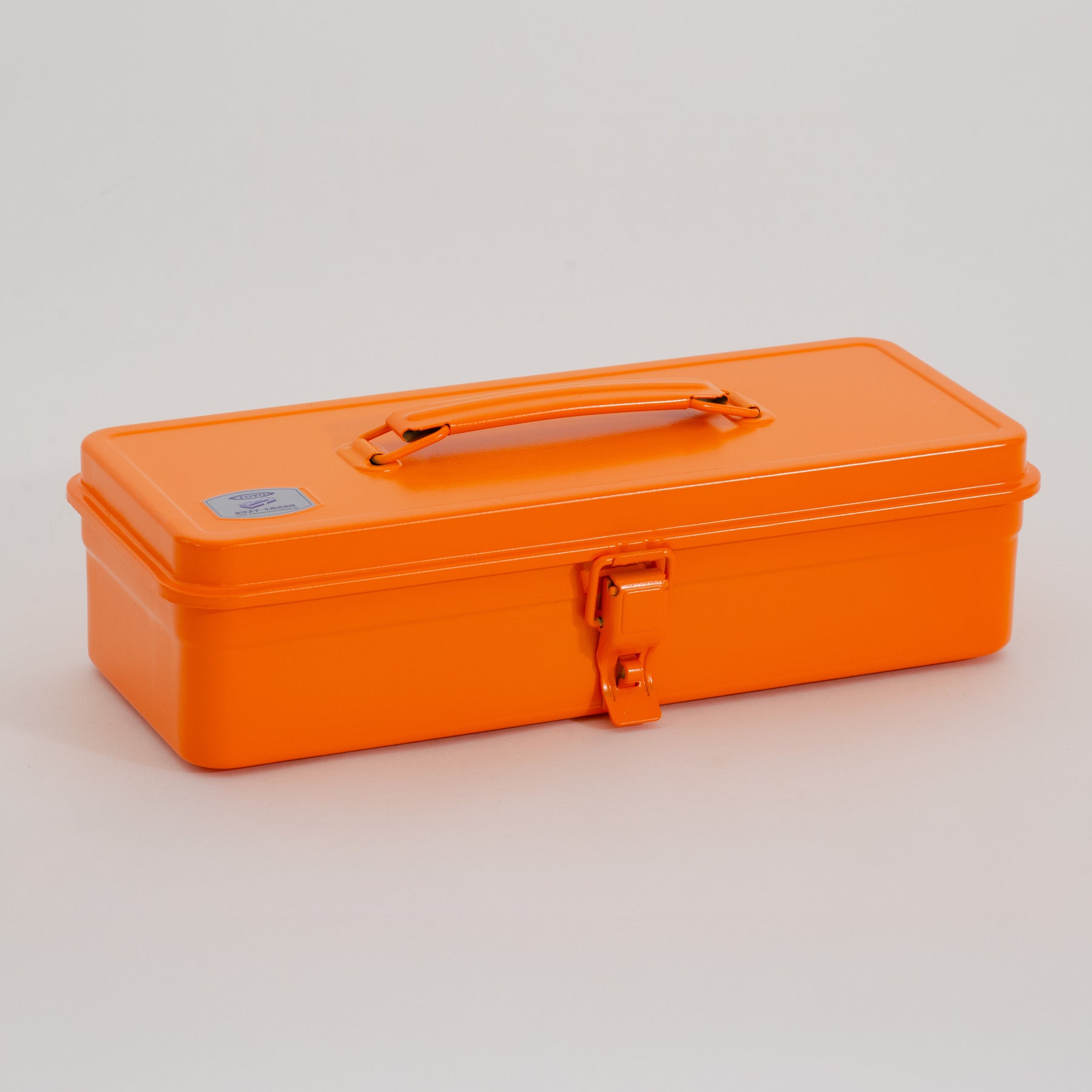 Closed orange Toyo Steel metal toolbox with top handle and single front latch, photographed on a light gray studio background.