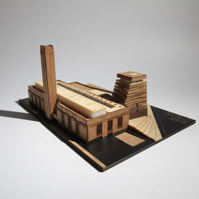 Wooden model of a building on a black base with a white background