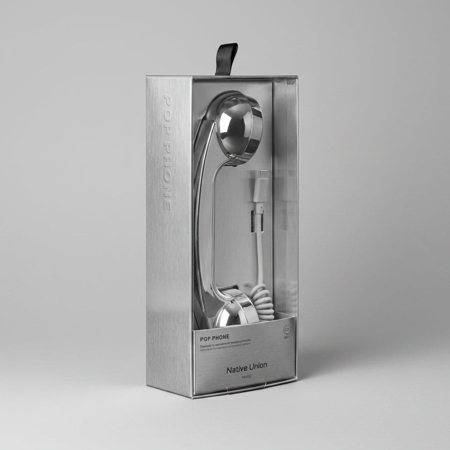 A silver metallic flip-style cord telephone in its original retail packaging, featuring a brushed metal box with a clear window and a black hanging tab.