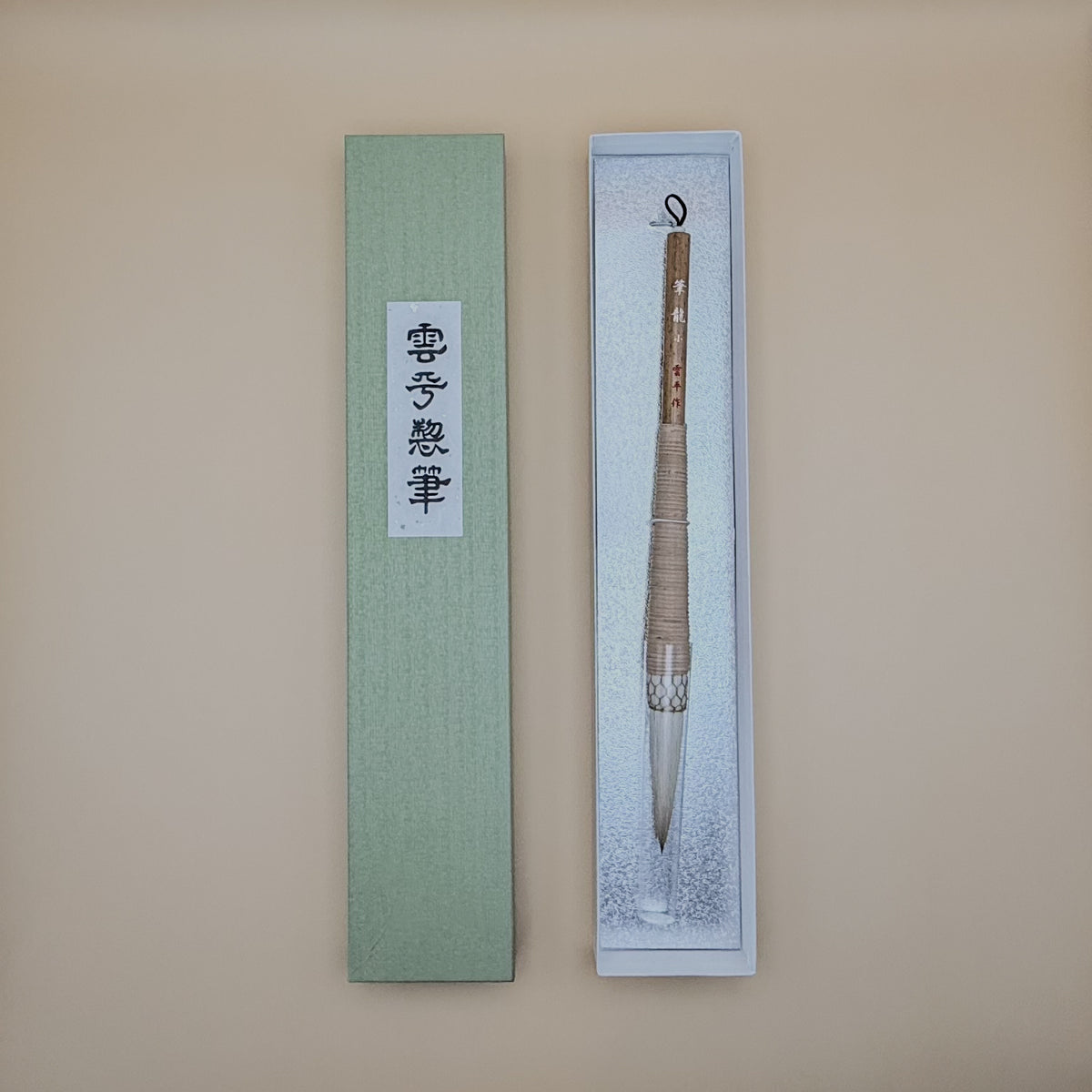 Traditional Chinese calligraphy brush in a decorative box on a beige background