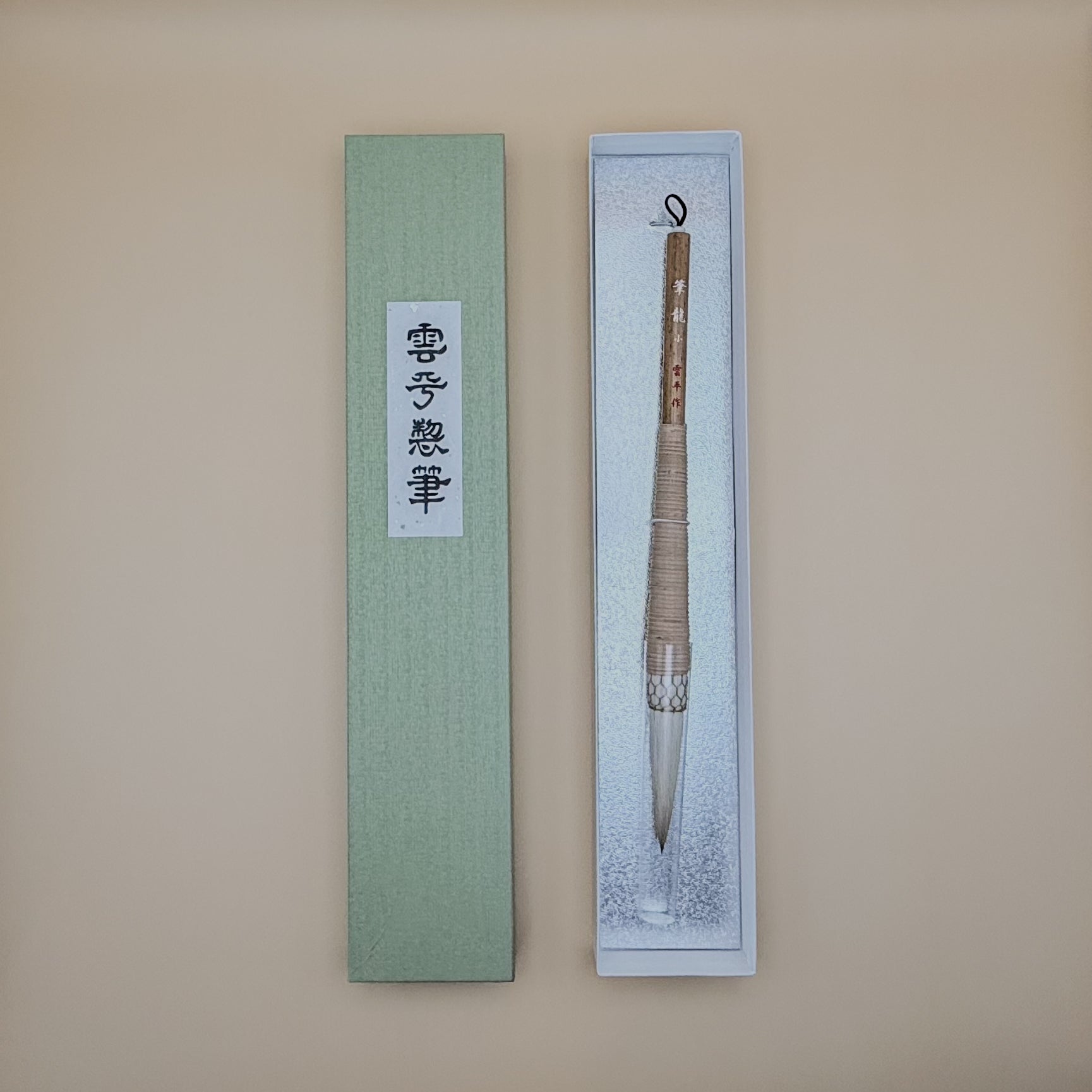 Traditional Chinese calligraphy brush in a decorative box on a beige background