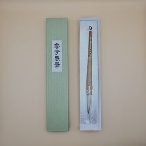 Traditional Chinese calligraphy brush in a decorative box on a beige background