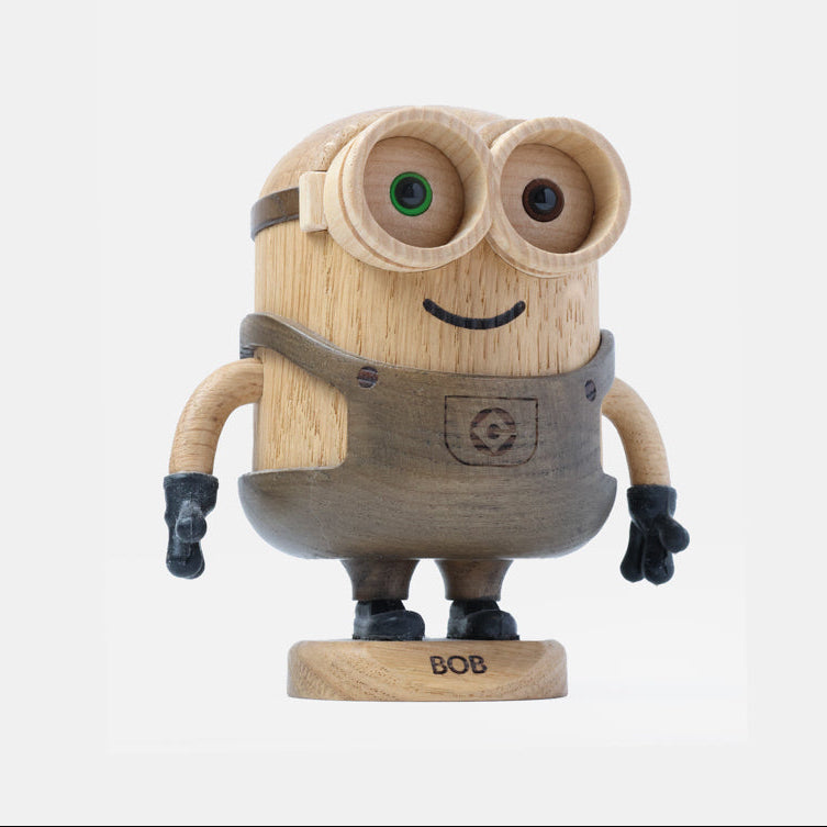 Wooden Minion character figurine with carved goggles, smiling face, gray overalls, black gloves, and boots, standing on a round wooden base labeled “Bob”.