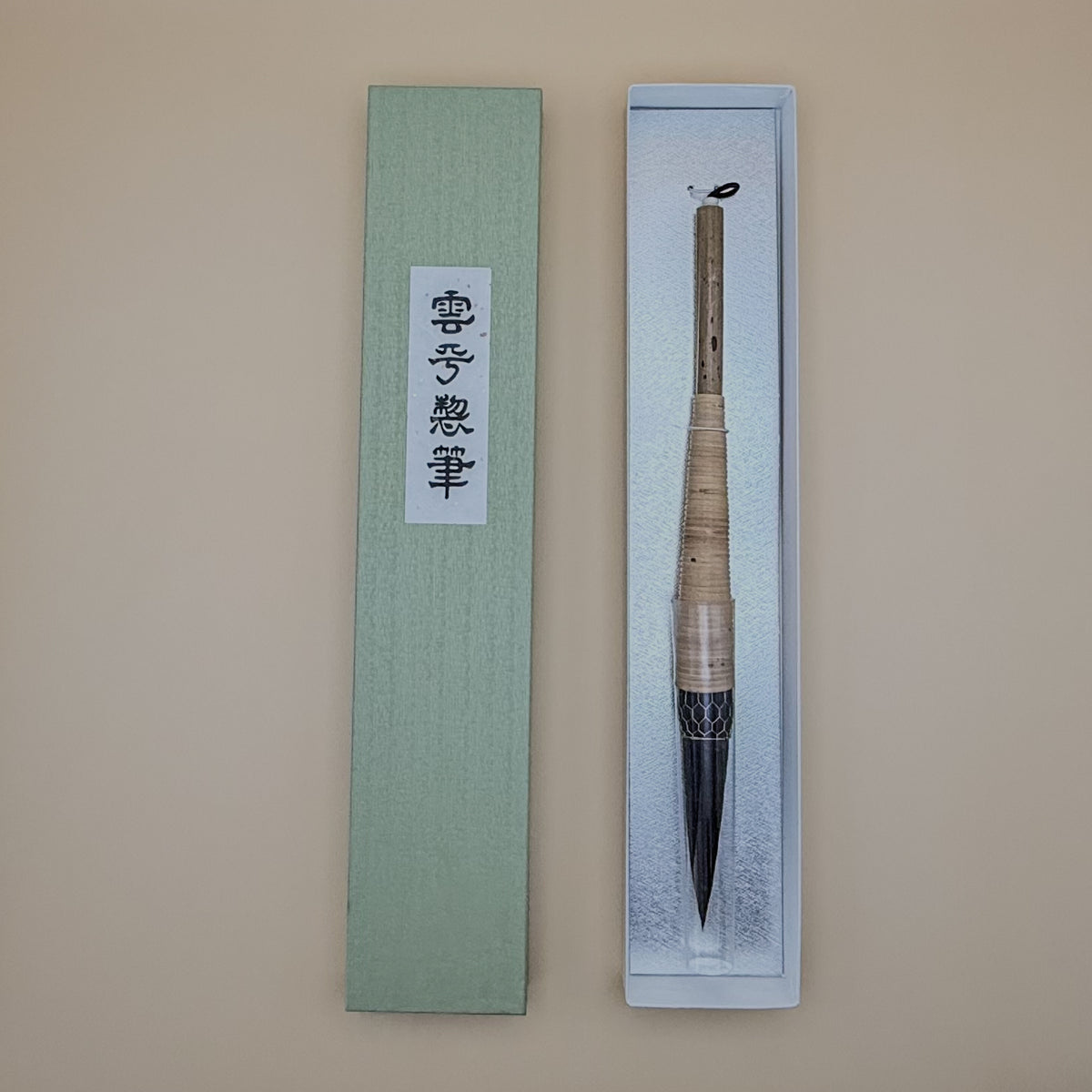 Traditional Chinese calligraphy brush in a decorative box on a beige background