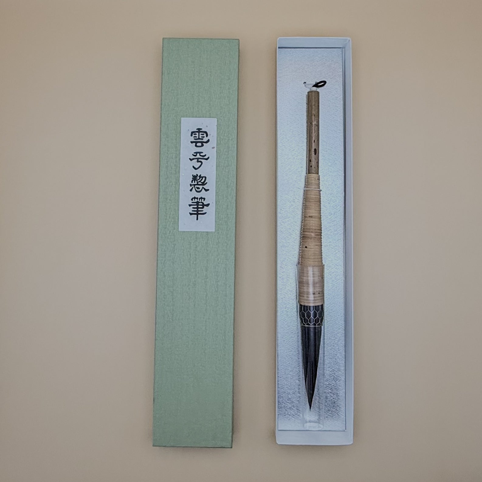 Traditional Chinese calligraphy brush in a decorative box on a beige background