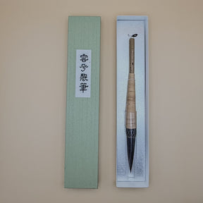 Traditional Chinese calligraphy brush in a decorative box on a beige background