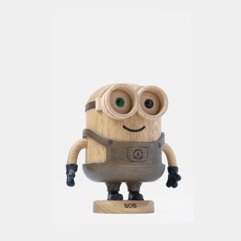 Wooden Minion character figurine with carved goggles, smiling face, gray overalls, black gloves, and boots, standing on a round wooden base labeled “Bob”.