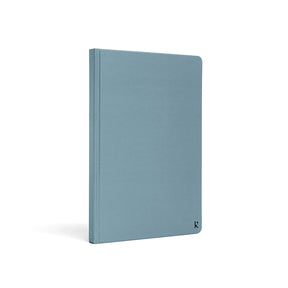 Karst A5 stone paper notebook with a soft blue hard cover, shown at a three-quarter angle on a white background, featuring a minimalist design and subtle embossed Karst logo in the lower corner.