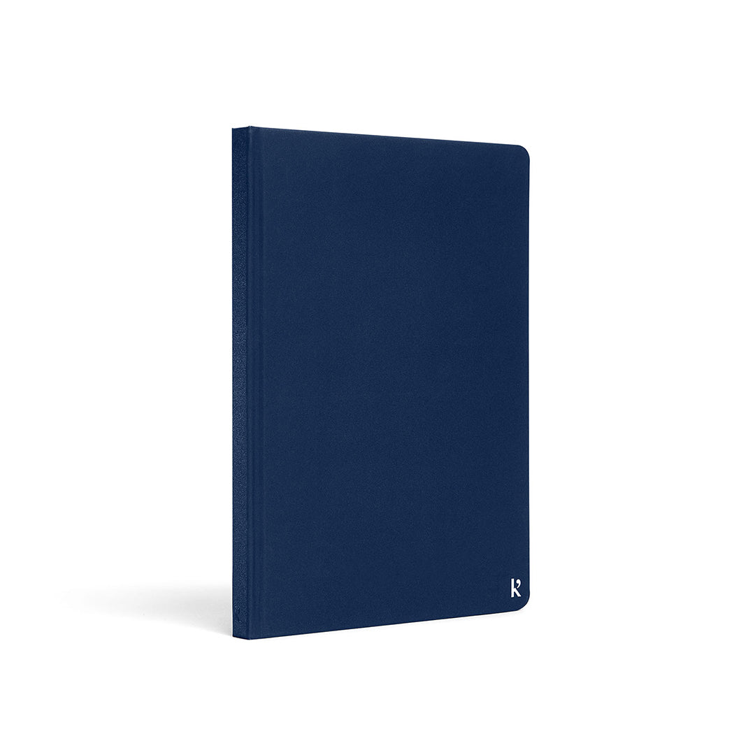 Karst A5 stone paper notebook with a navy blue hard cover, shown at a three-quarter angle on a white background, featuring a clean minimalist design and a subtle embossed Karst logo in the lower corner.