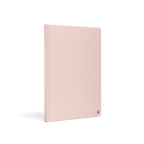 Karst A5 hardcover stone paper notebook in soft blush pink with rounded corners and minimalist logo detail, standing upright on a light gray background.
