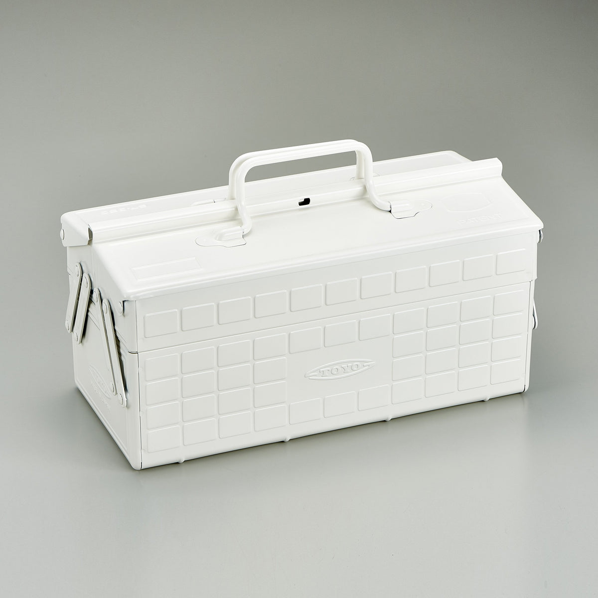 White Toyo steel cantilever toolbox, closed, shown at a three-quarter angle with embossed grid panels, folded side arms, and a fixed top handle against a neutral studio background.