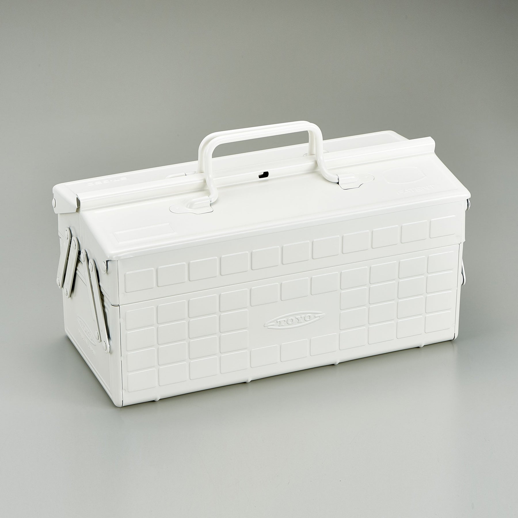 White Toyo steel cantilever toolbox, closed, shown at a three-quarter angle with embossed grid panels, folded side arms, and a fixed top handle against a neutral studio background.