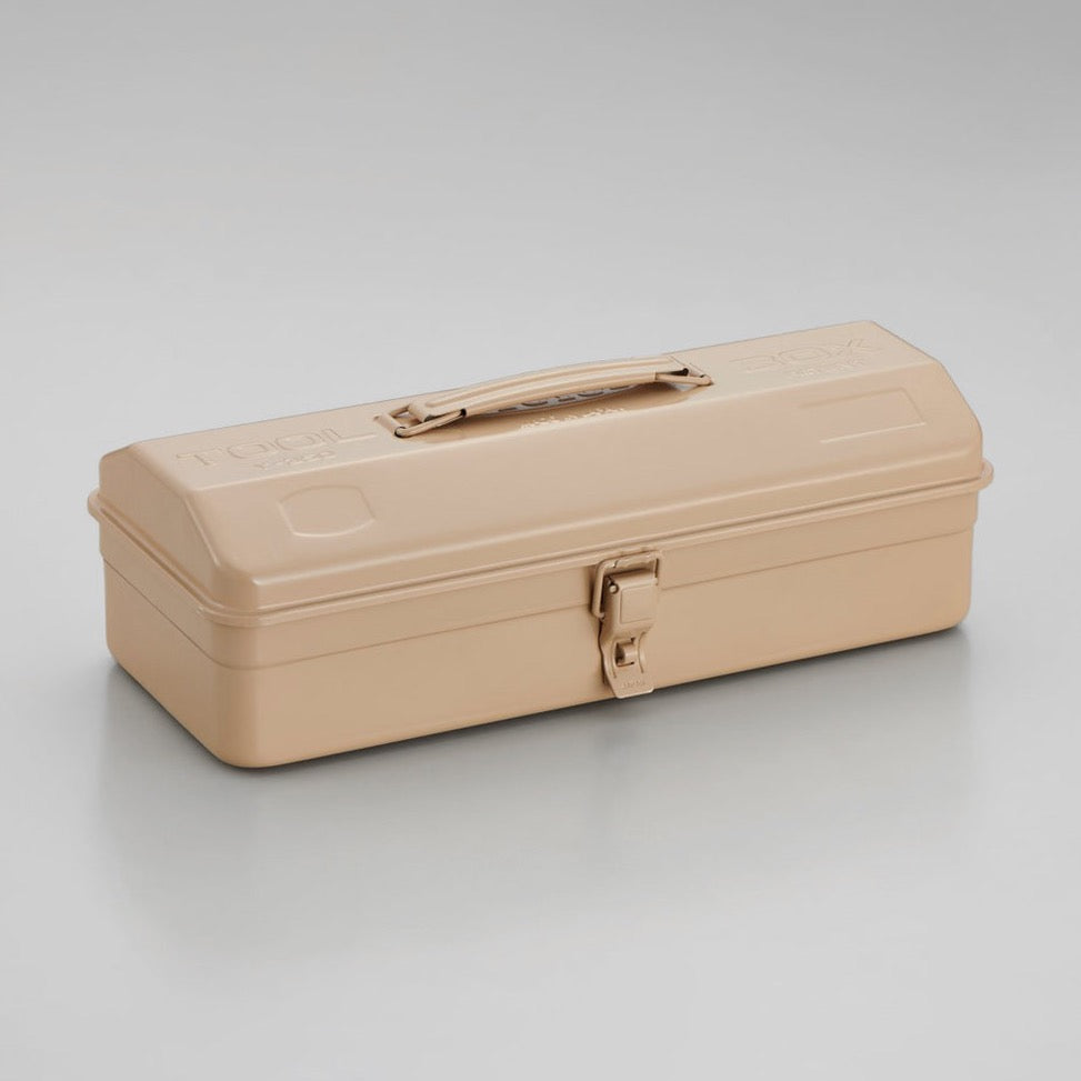 Beige Toyo Y-350 steel toolbox with smooth matte finish, rounded rectangular lid, integrated top handle, and single front latch, shown closed on a neutral gray studio background.